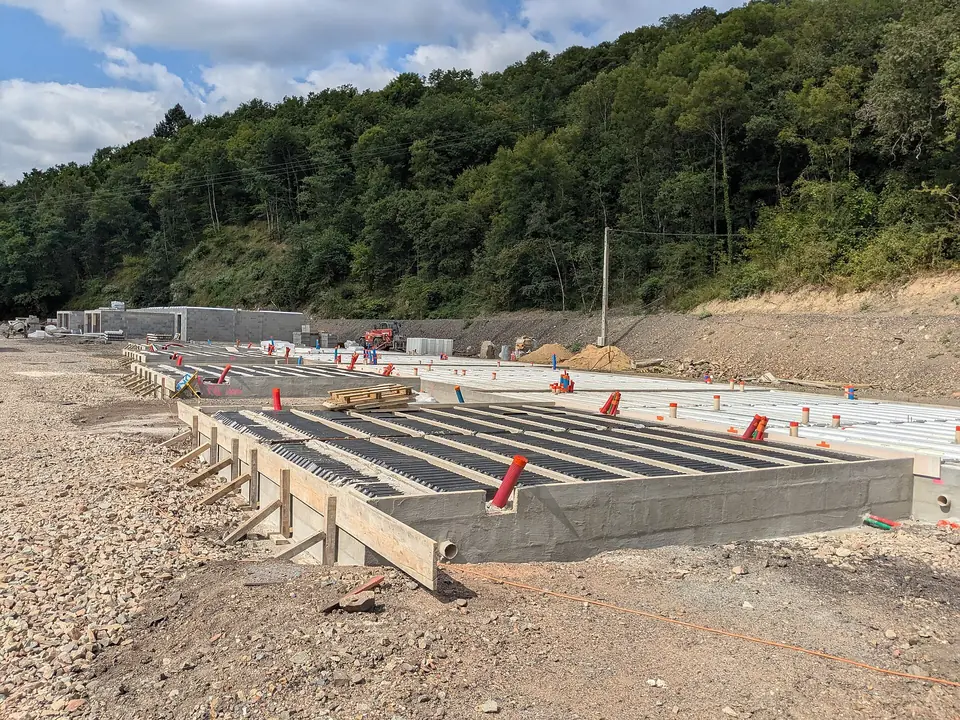Plancher en poutrelles et hourdis posé sur un soubassement en béton à Chamelet, sur un terrain empierré au pied d'une colline boisée.